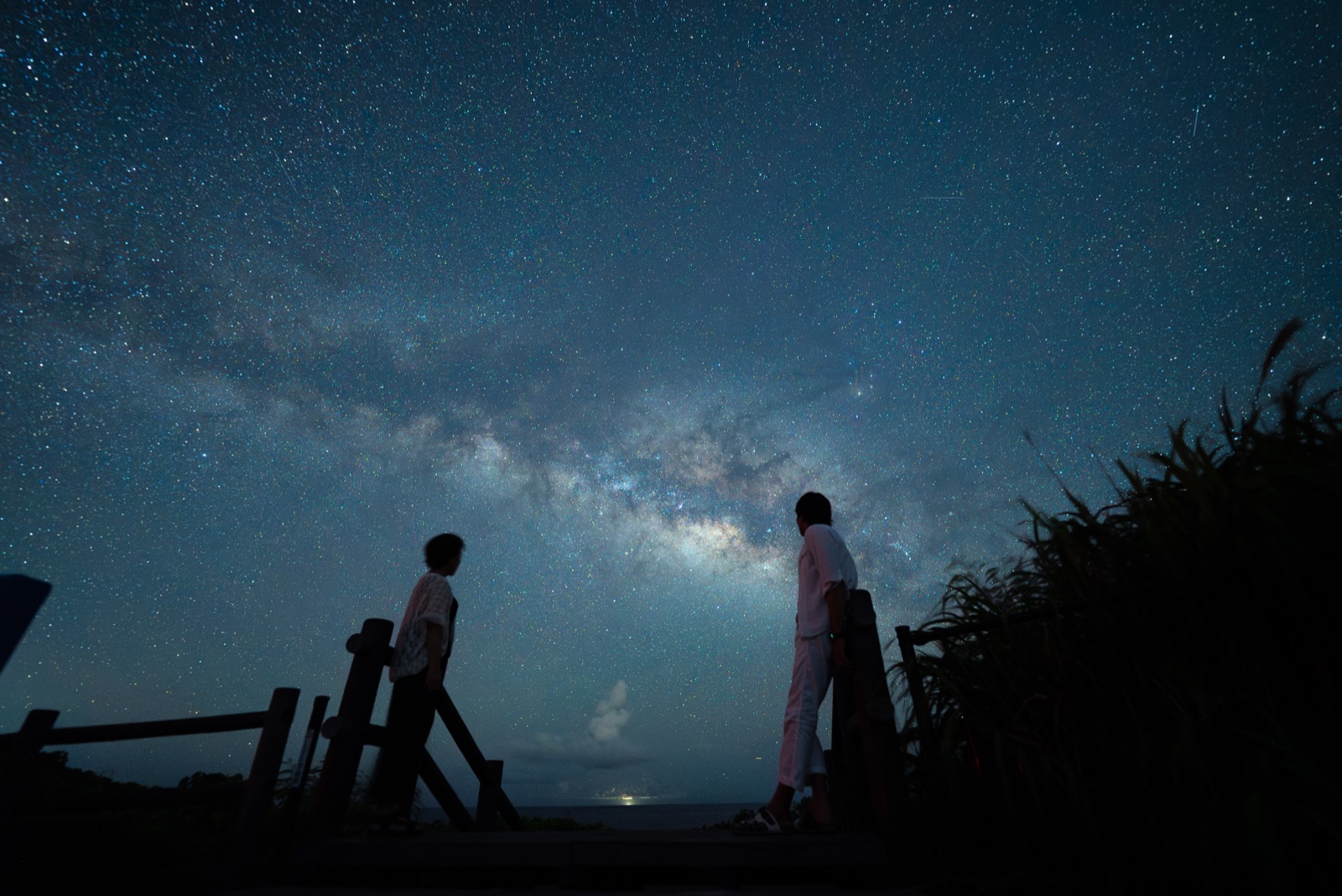 宮古島の天の川が広がる夜空の下、デッキで向き合う二人